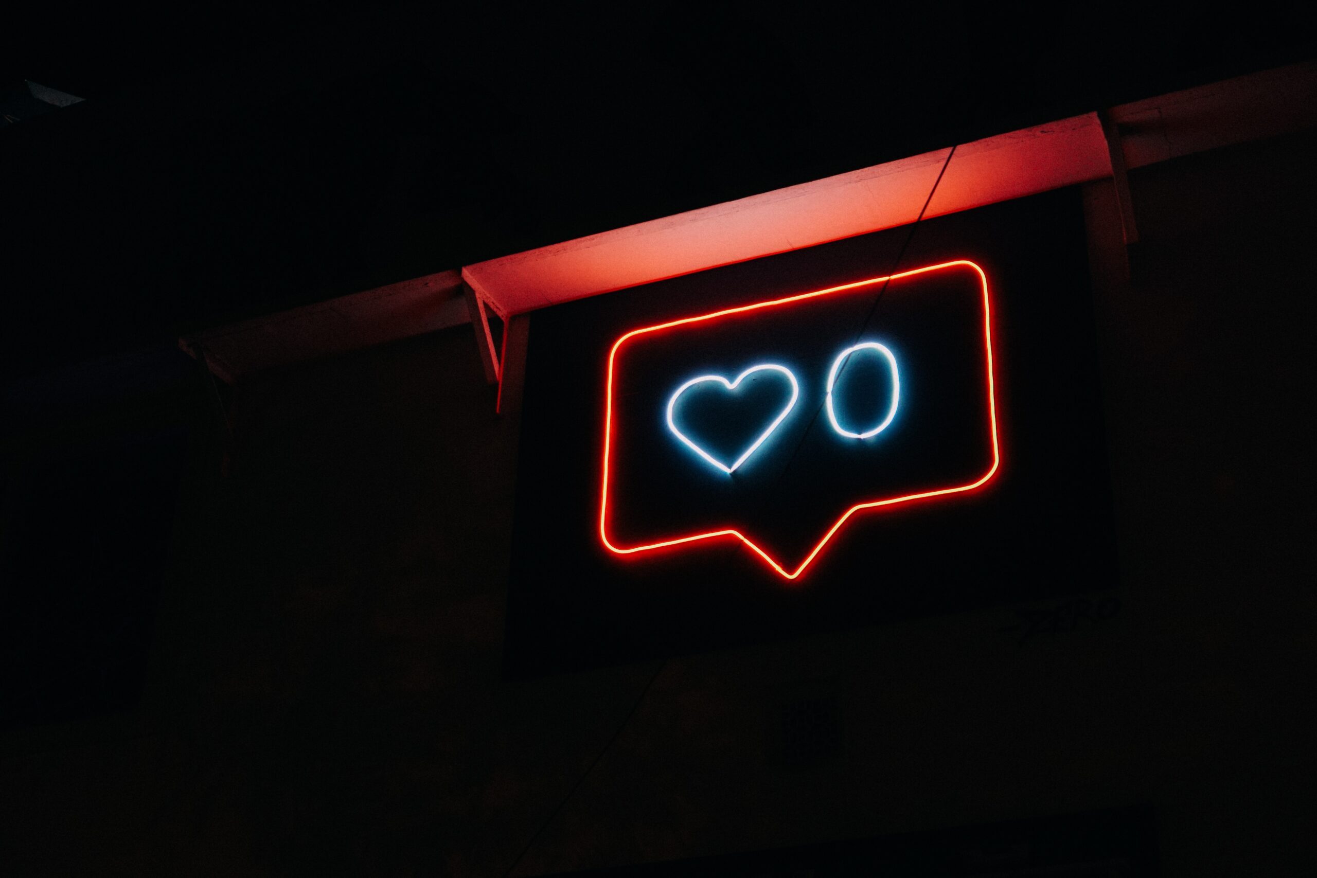 Schwarzer Hintergrund mit einem Neon-Schild, welches ein "Like"-Symbol mit einer "0" darstellt.