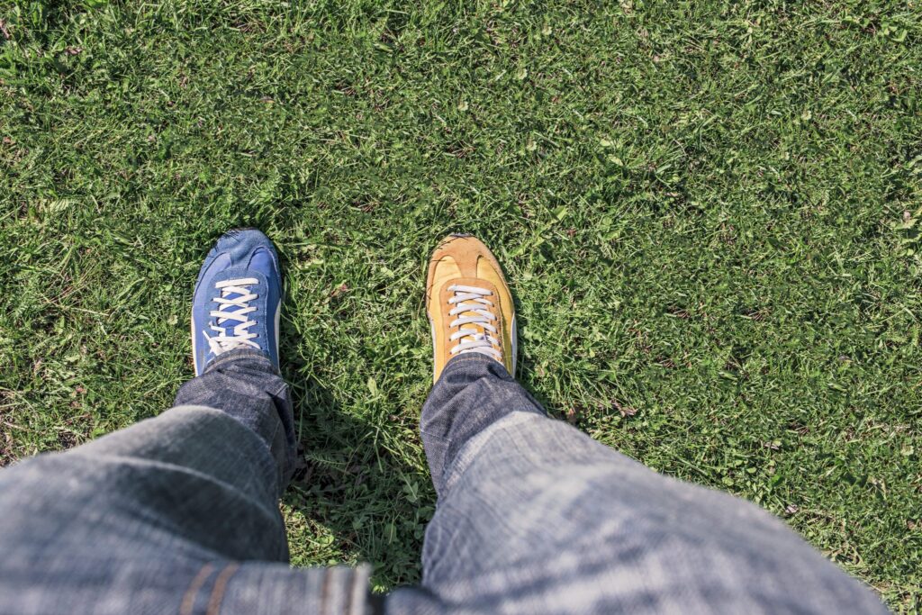 Mann steht mit einem blauen und einem gelben Schuh auf einer Wiese - zur Veranschaulichung eines A/B-Test