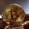 Eine goldene Bitcoin Münze steht auf weiteren liegenden Münzen
