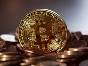 Eine goldene Bitcoin Münze steht auf weiteren liegenden Münzen