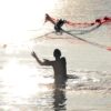 Mann steht im Meer und wirft ein rot-blaues Fischernetz in die Luft - zur Veranschaulichung des Vorteils einer Landingpage