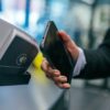 Eine Person hält sein Smartphone gegen ein Kassenterminal, um über Google Pay zu bezahlen