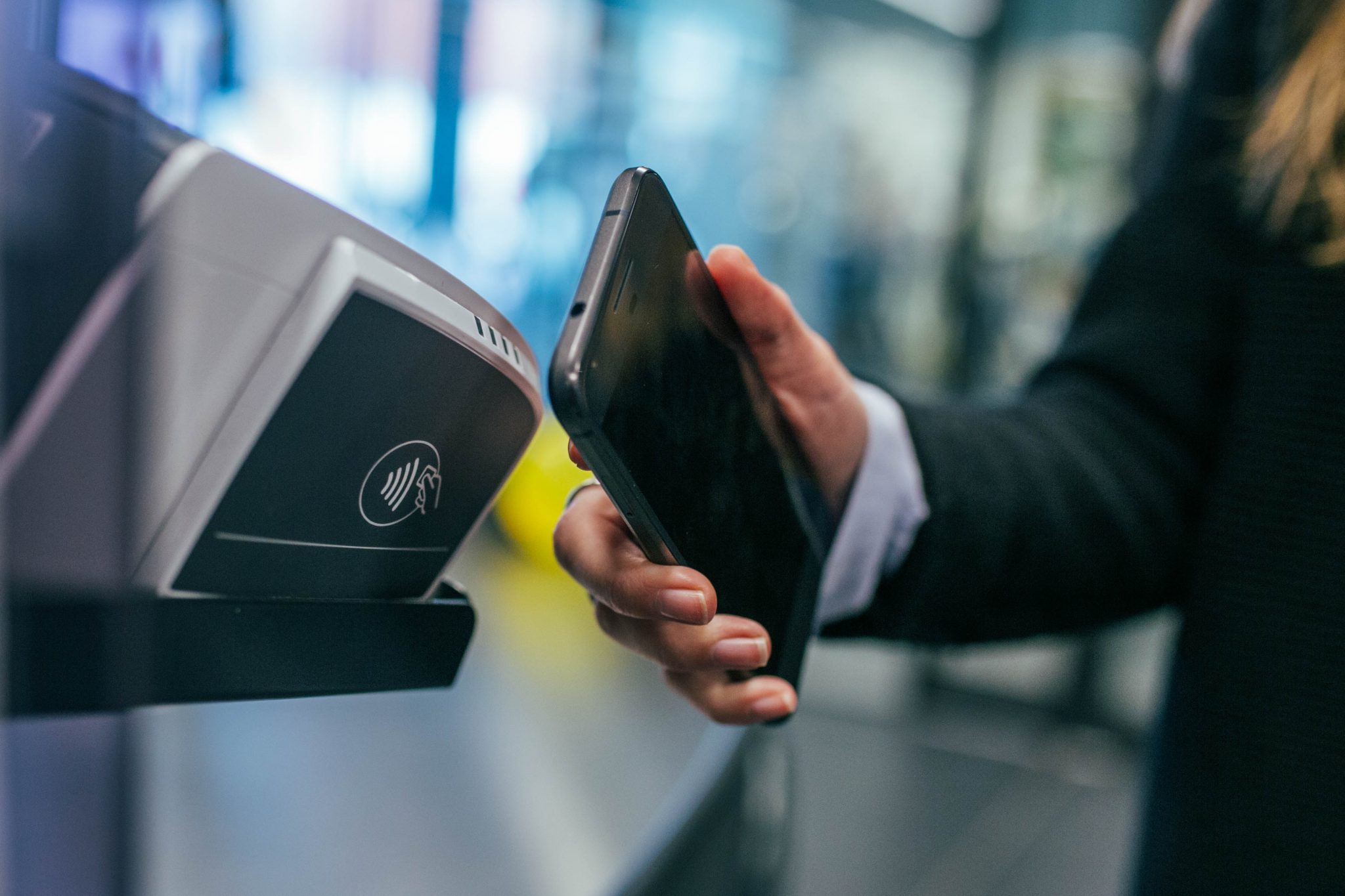 Eine Person hält sein Smartphone gegen ein Kassenterminal, um über Google Pay zu bezahlen