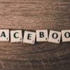 Holztisch mit Scrabble Steinen auf die denen Facebook steht