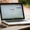 Macbook auf dem Google steht und Handy auf Holztisch