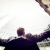 Mann im Anzug breitet seine Hände aus und schaut zu einem hohen Gebäude auf - Blogartikel zur Internetwerbung