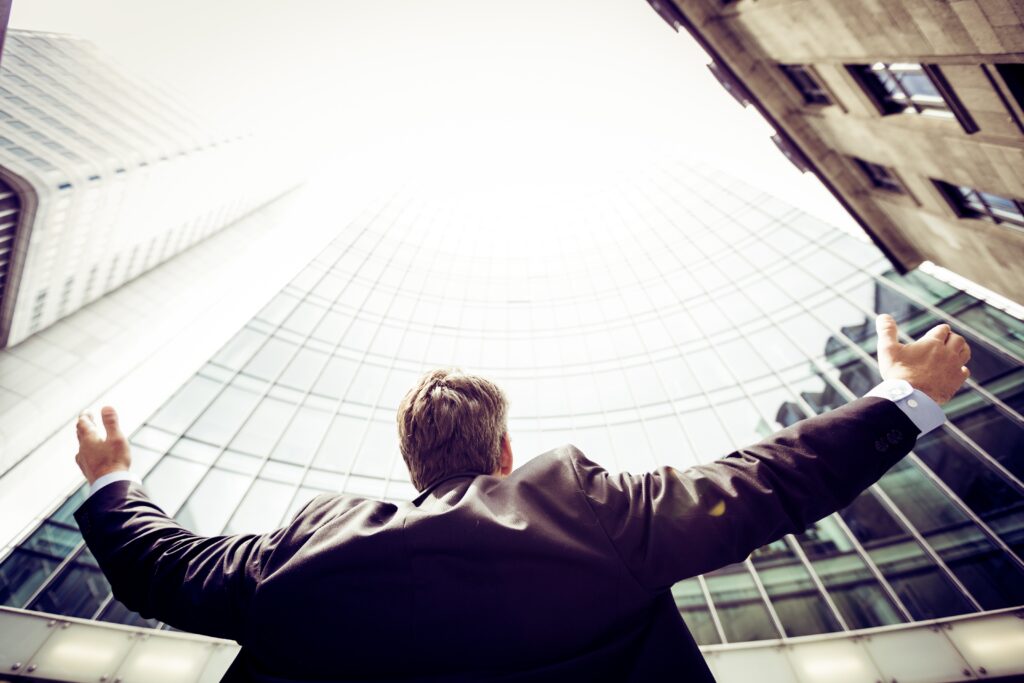 Mann im Anzug breitet seine Hände aus und schaut zu einem hohen Gebäude auf - Blogartikel zur Internetwerbung