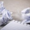 Schreibblock mit zerknüllten Blättern daneben. Zur Veranschaulichung des Blogbeitrags wie man einen guten Webtext schreibt.