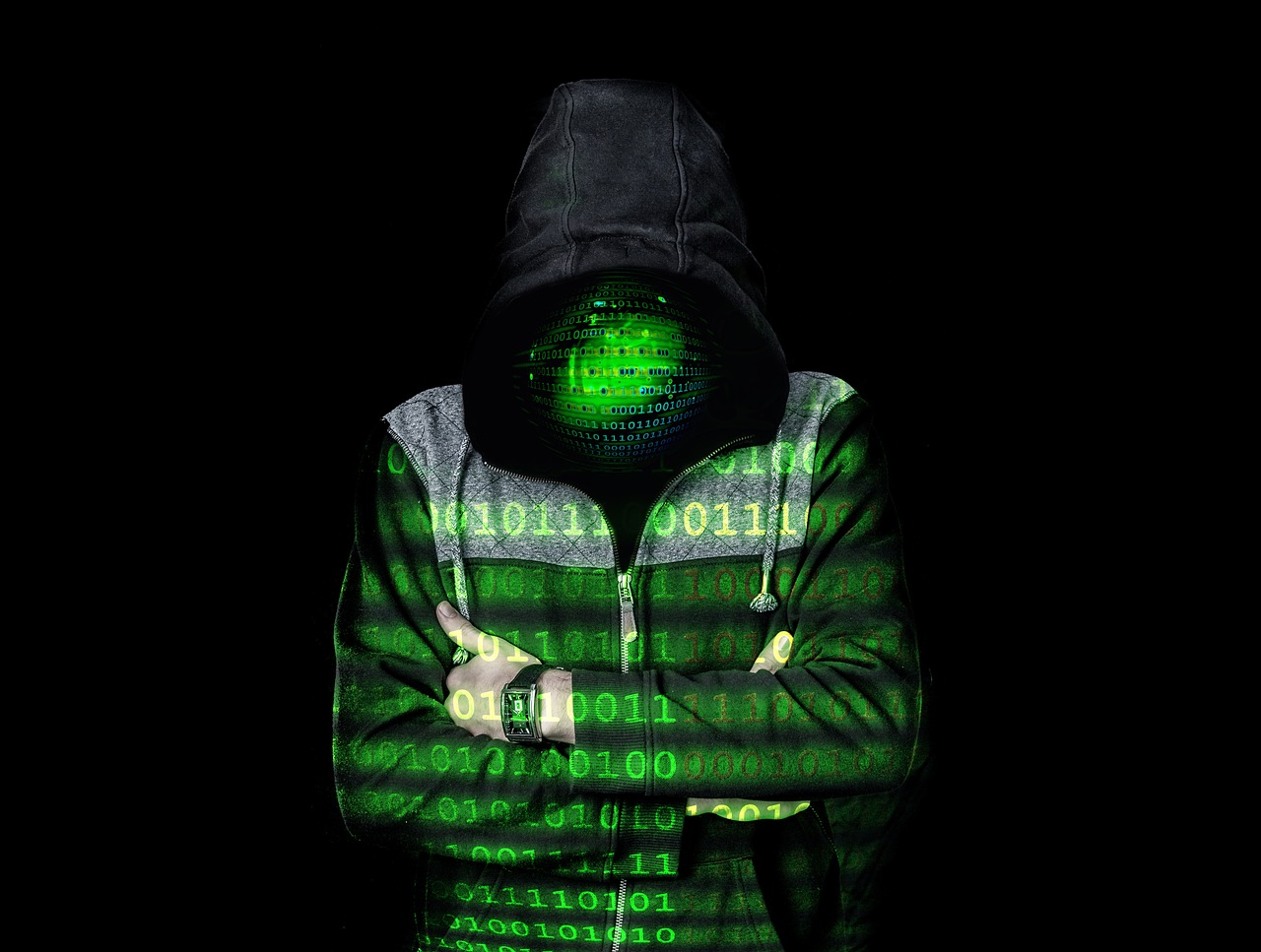 Ein Mann im Kapuzenpulli vor schwarzem Hintergrund, auf ihm in grün Nullen und Einsen projiziert. Sein Gesicht nicht zu erkennen, ersetzt durch grüne Nullen und Einsen.