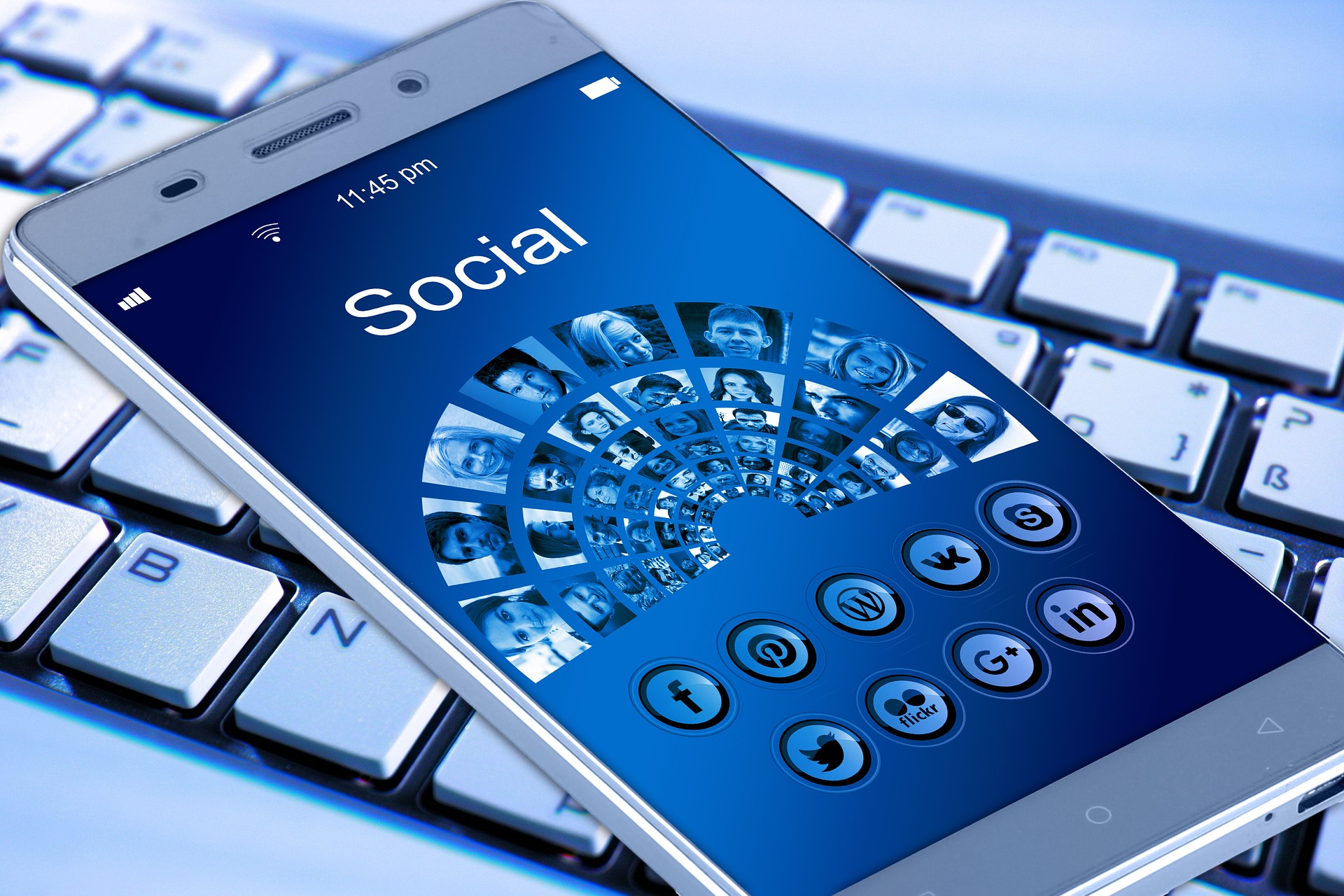 Ein Smartphone liegt auf einer Tastatur. Auf dem Bildschirm sind verschiedene Icons von sozialen Medien zu sehen.