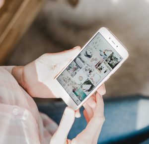 Frau hat Smartphone in der Hand - Blogbeitrag: Wie Du eigene Sticker in Deiner Instagram Story nutzt