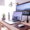 Holzschreibtisch auf dem geöffnetes Macbook und PC stehen - Blog: Webseite für Unternehmen