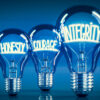 Leuchtende Glühbirnen mit Wörtern zum Thema Respekt und Umgang auf blauem Hintergrund
