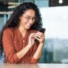 Frau schaut auf Handy und lächelt