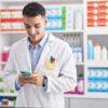 Apotheker schaut auf Handy und lächelt