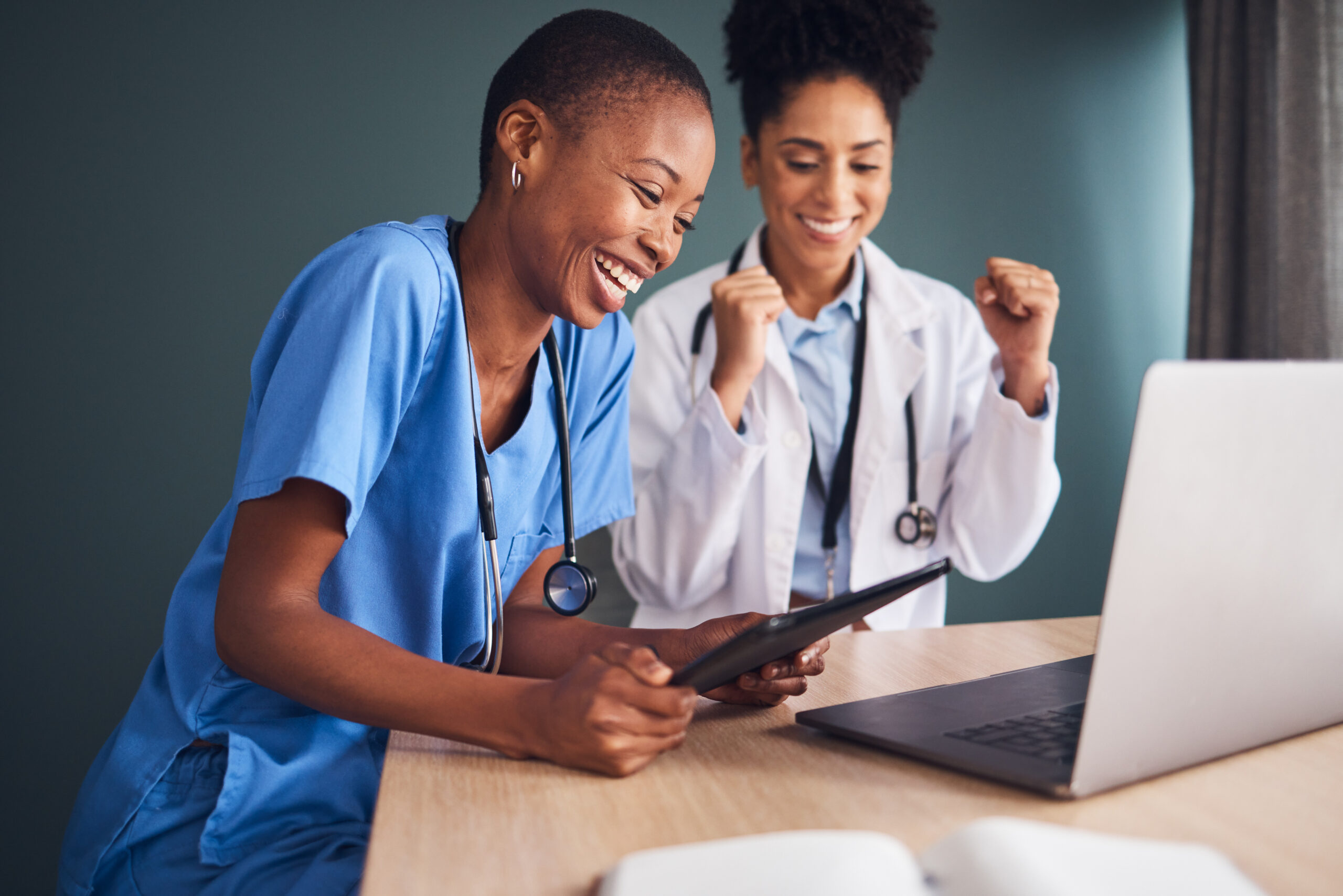 Zwei Ärzte schauen auf Bildschirm und freuen sich über Online-Marketing-Erfolg