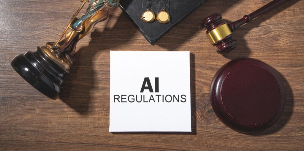 &bdquo;AI Regulations&ldquo; auf einem Schreibtisch mit Richterhammer, Justitia-Statue und juristischen Symbolen &ndash; Sinnbild f&uuml;r KI-Gesetze, Compliance und rechtliche Rahmenbedingungen k&uuml;nstlicher Intelligenz.