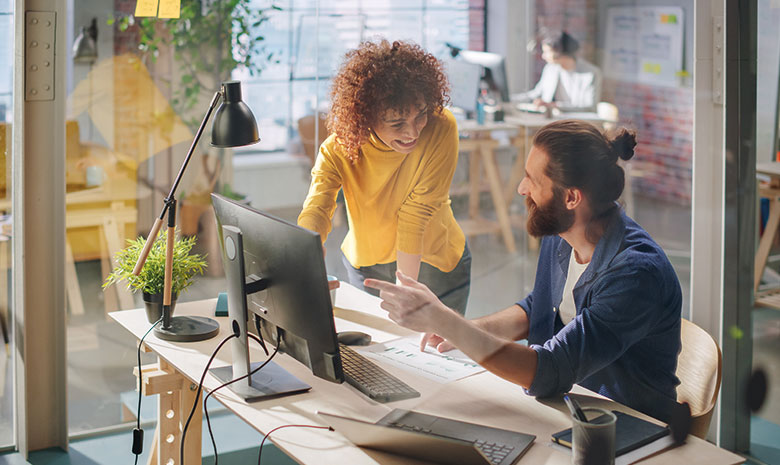Zwei Teammitglieder besprechen eine Strategie am Computer im Büro