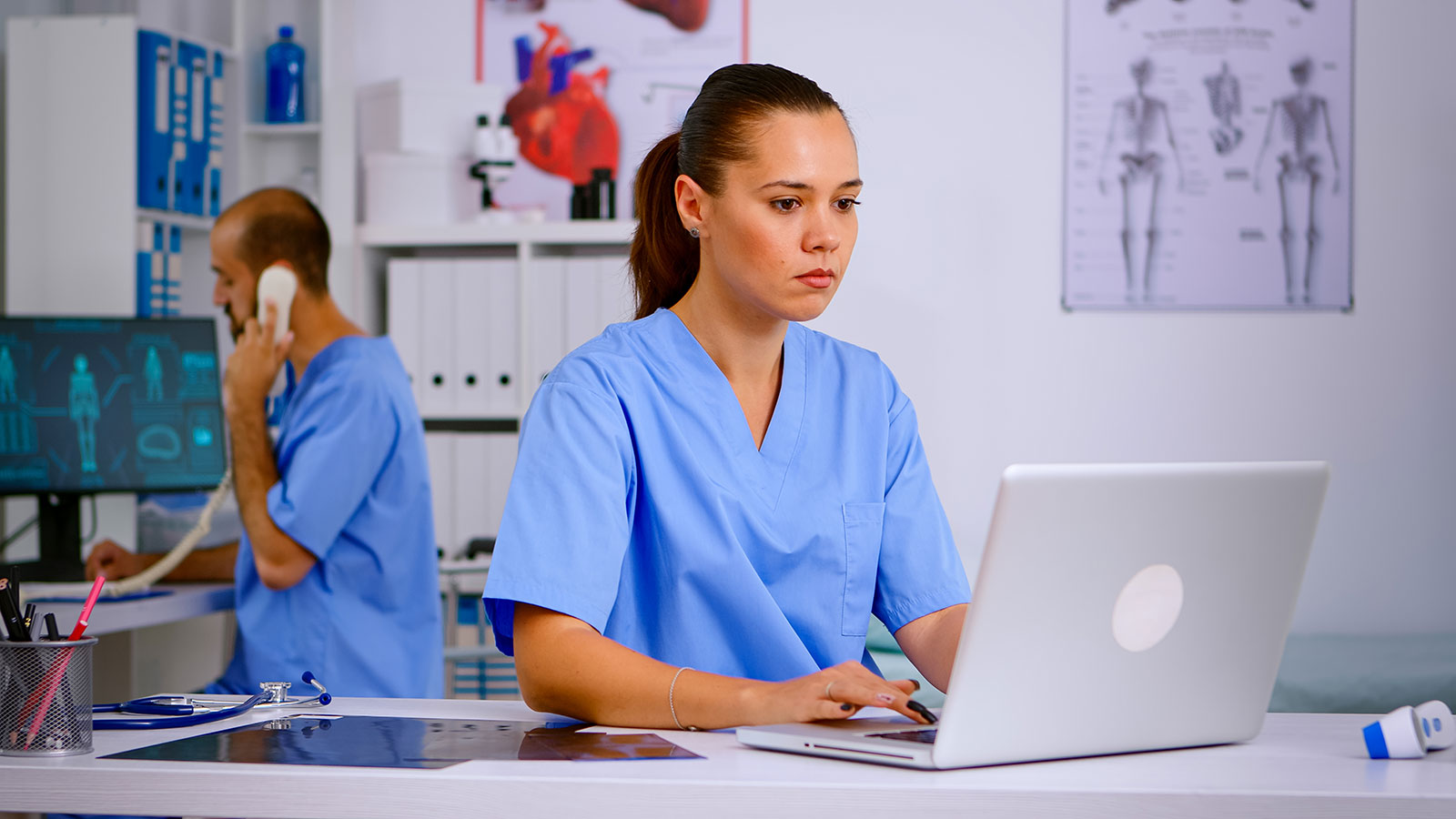 Medizinische Angestellte sitzt in einem Büro vor einem Laptop